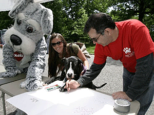 Event-goers and volunteers, including one enthusiastic canine, and the Maddie's Fund mascot, signed a card for animal activist and long-time TV game show host Bob Barker, who is retiring.